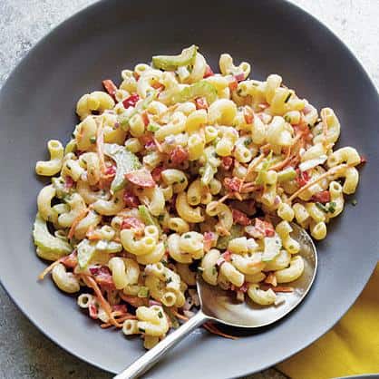  A colorful bowl full of Mama Mia's Macaroni Salad perfect for a summer backyard gathering.